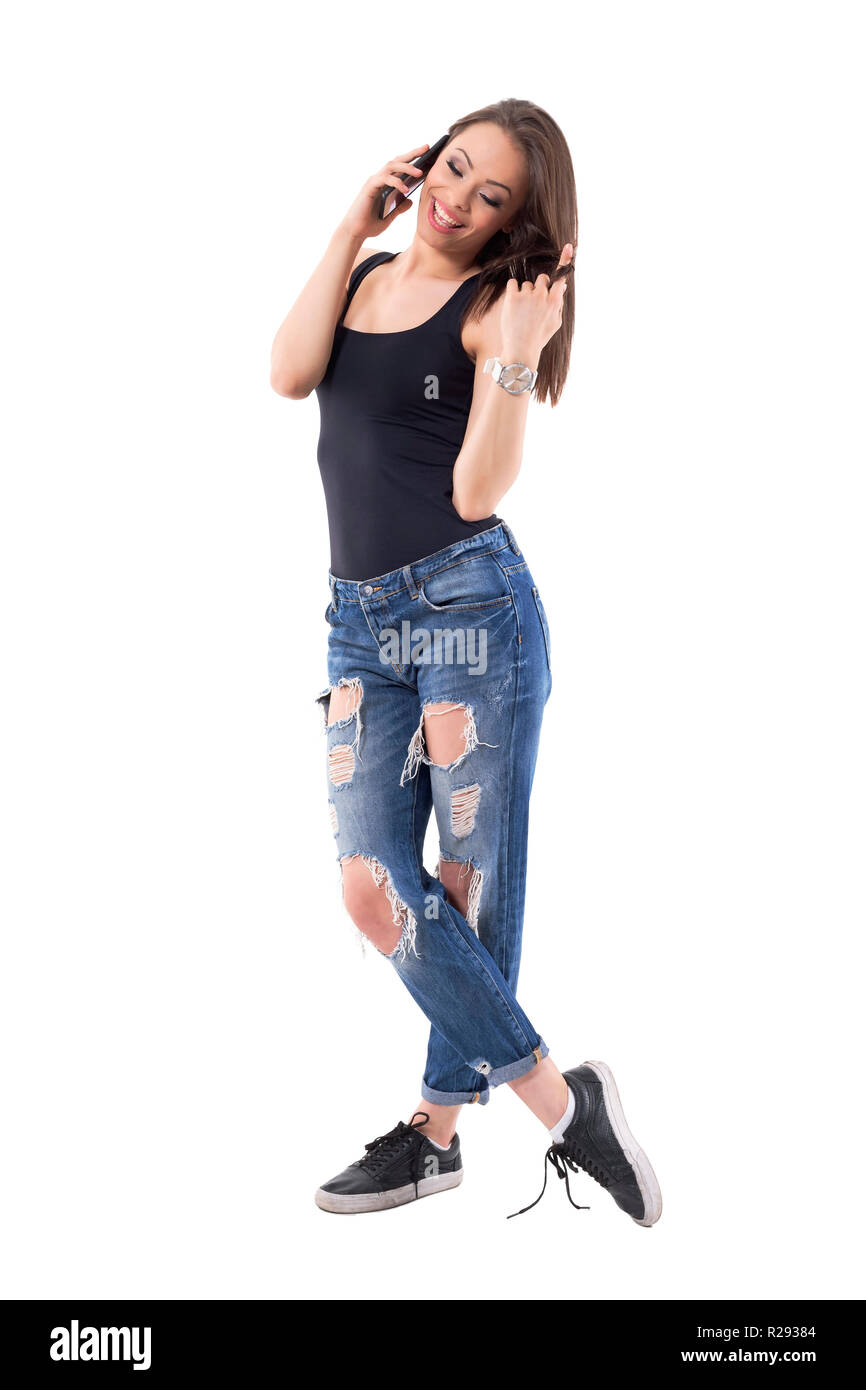 Leisure concept. Young beautiful happy woman relaxing talking on mobile phone and holding hair. Full body isolated on white background. Stock Photo