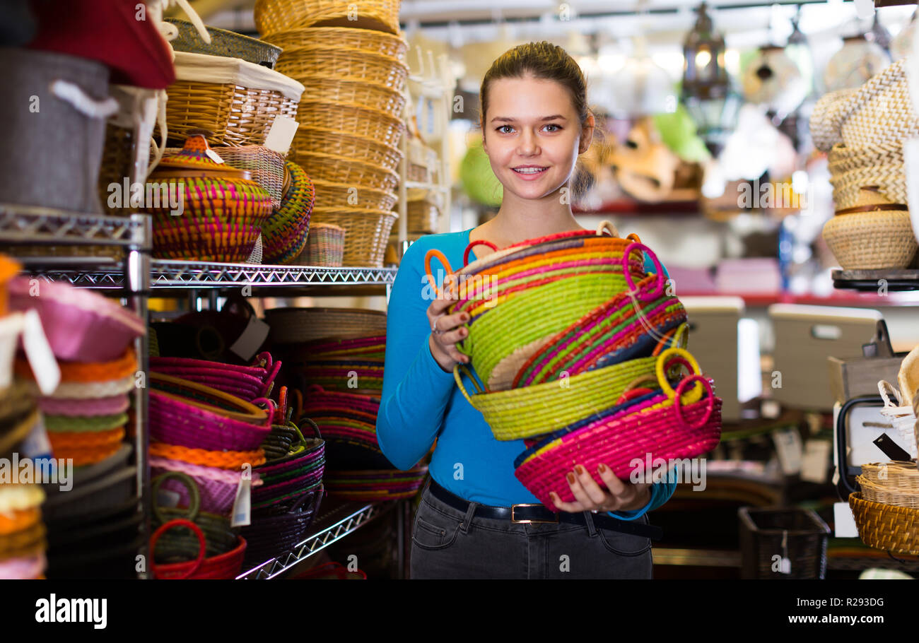Young female choosing colour wicker basket in decoration and store