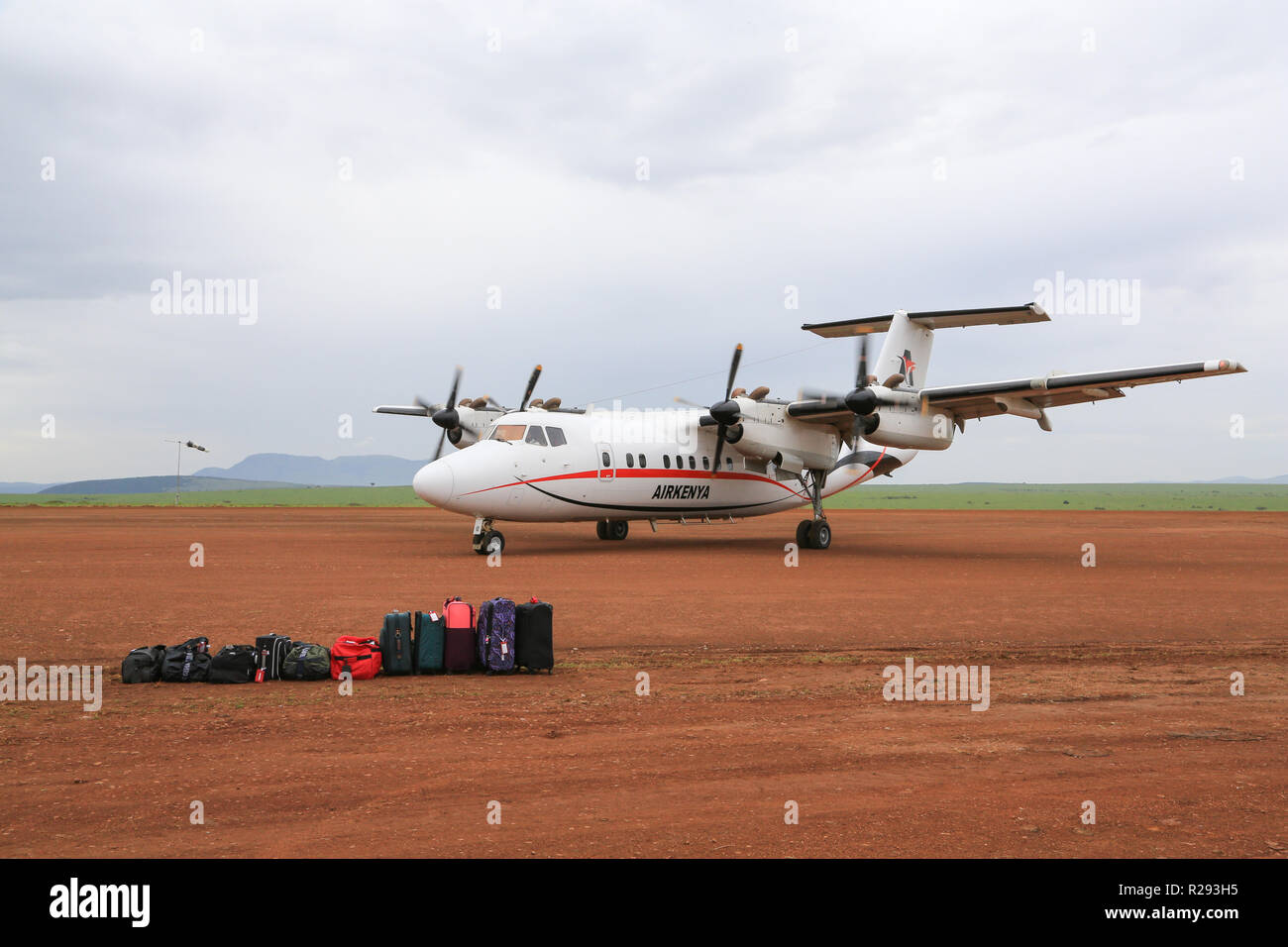 An Airkenya plane is taxiing toward waiting passengers and their luggage at the Keekorok Airstrip in Masai Mara National Reserve, Narok County, Kenya. Stock Photo