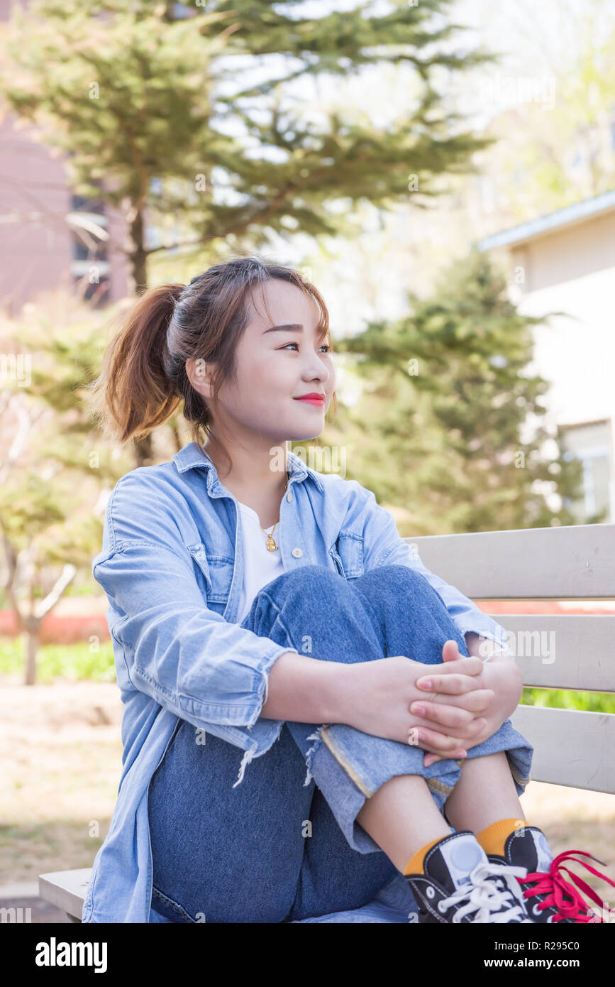 Young woman sitting on bench in university Stock Photo