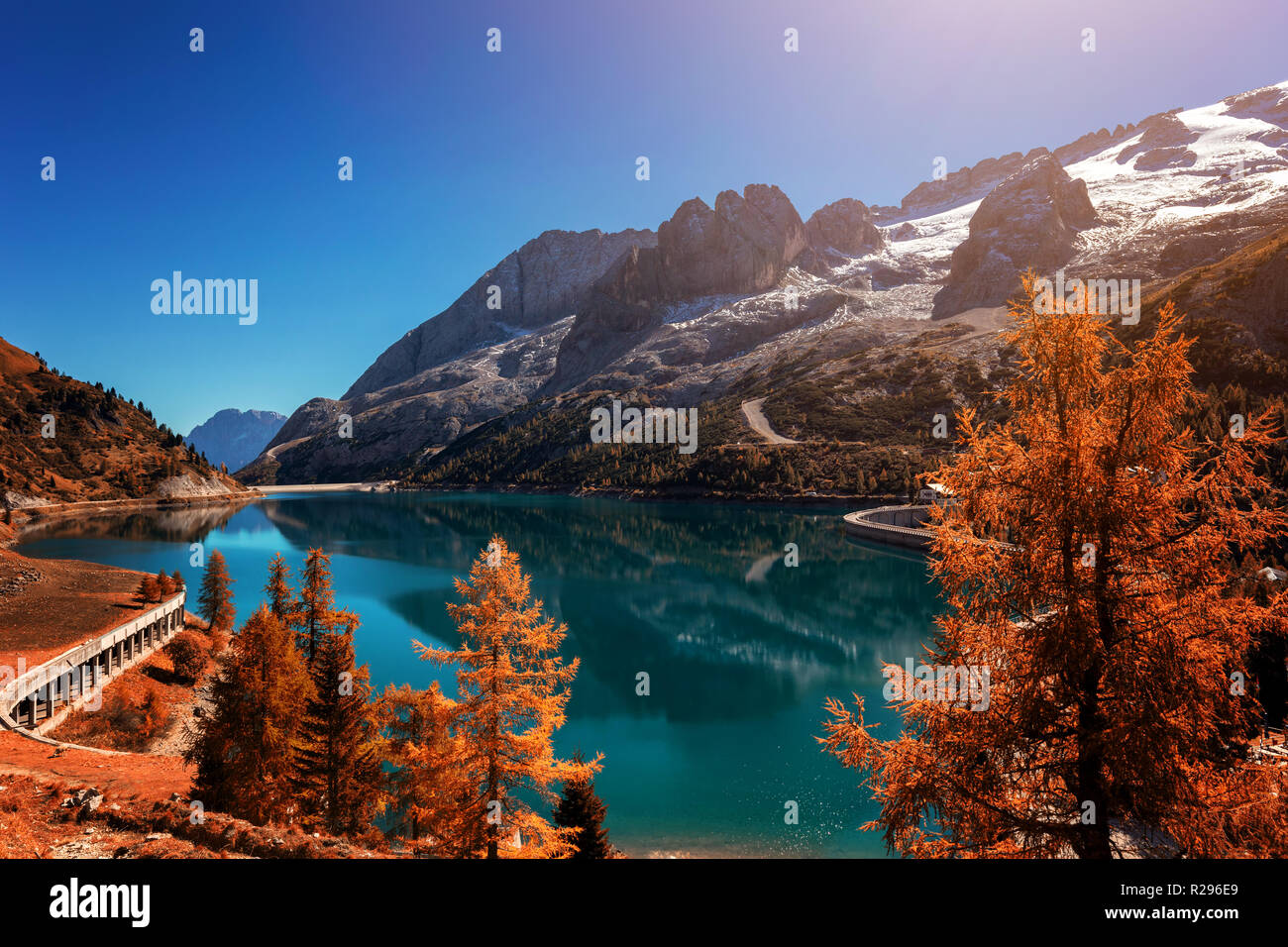 Beautiful autum colors at Fedaia lake with Marmolada peaks covered by ice, Dolomites, Italy Stock Photo