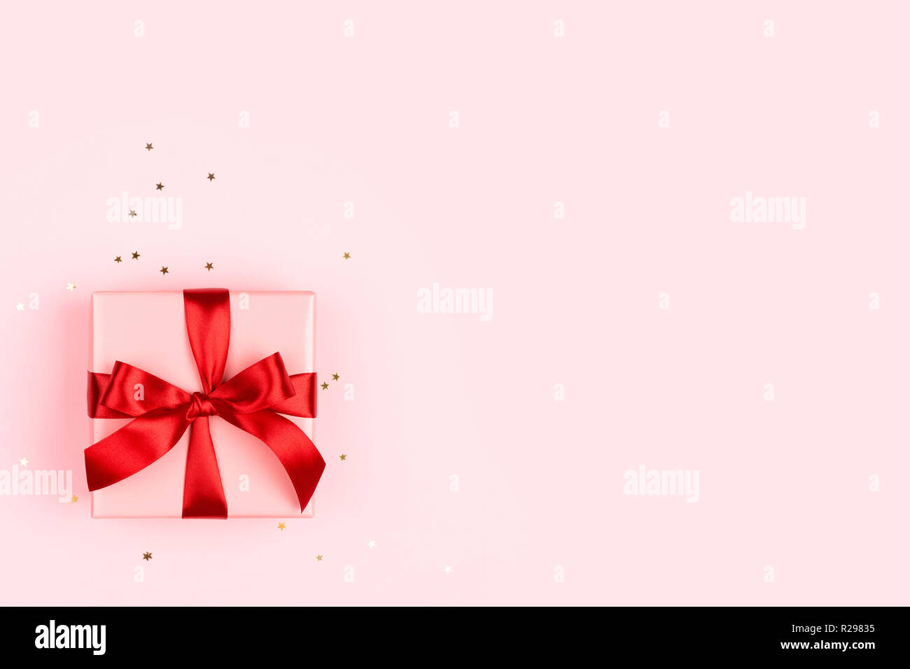 The pink gift box with red bow on the pink background with golden ...
