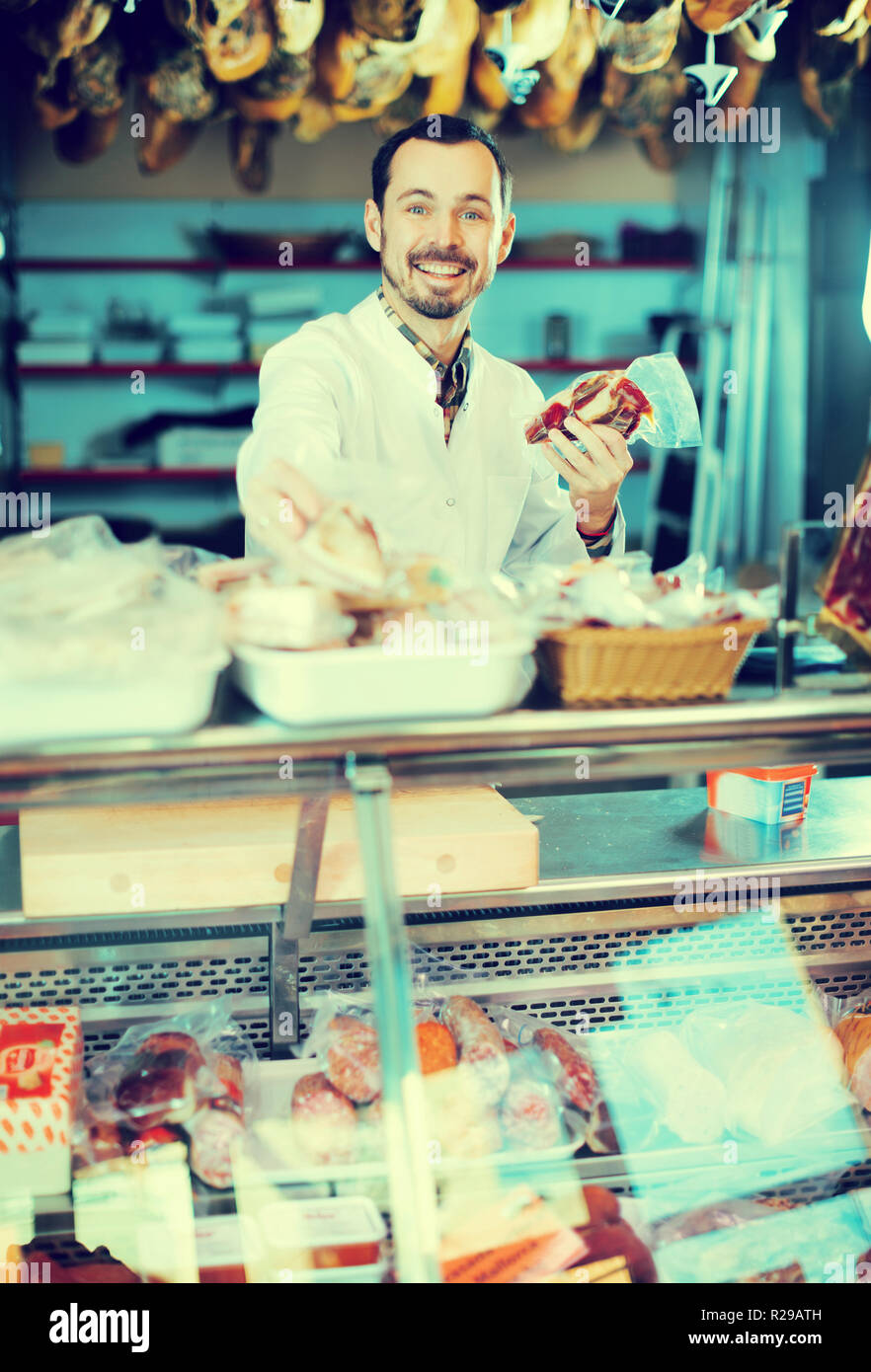 Smiling man seller showing sorts of meat in butcher’s shop Stock Photo ...