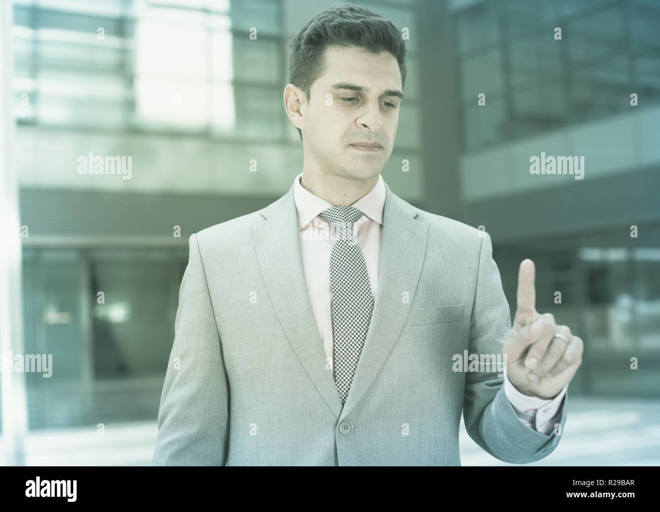 Businessman pressing imaginary button on large plant background Stock Photo
