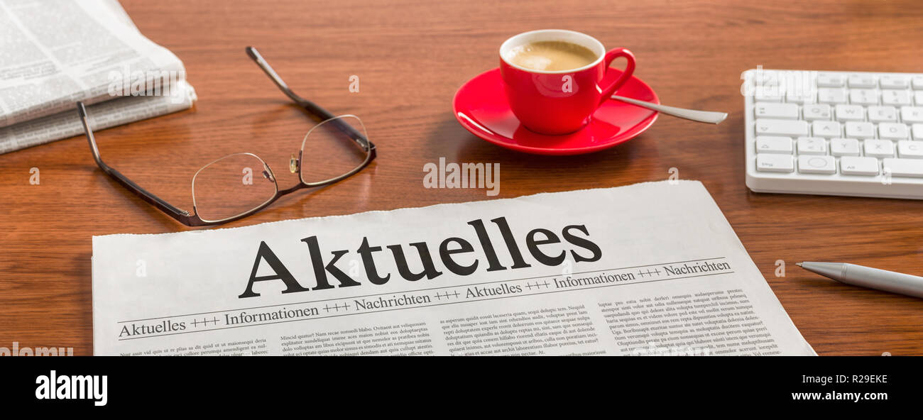 A newspaper on a wooden desk - Aktuelles (German word for Latest news) Stock Photo
