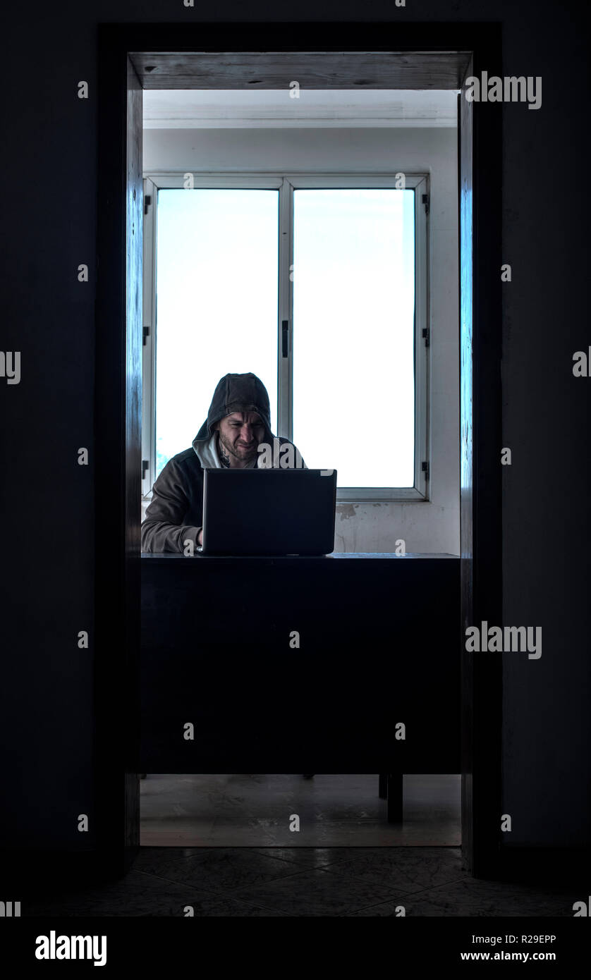 Hacker in a room with illuminated window. Stock Photo
