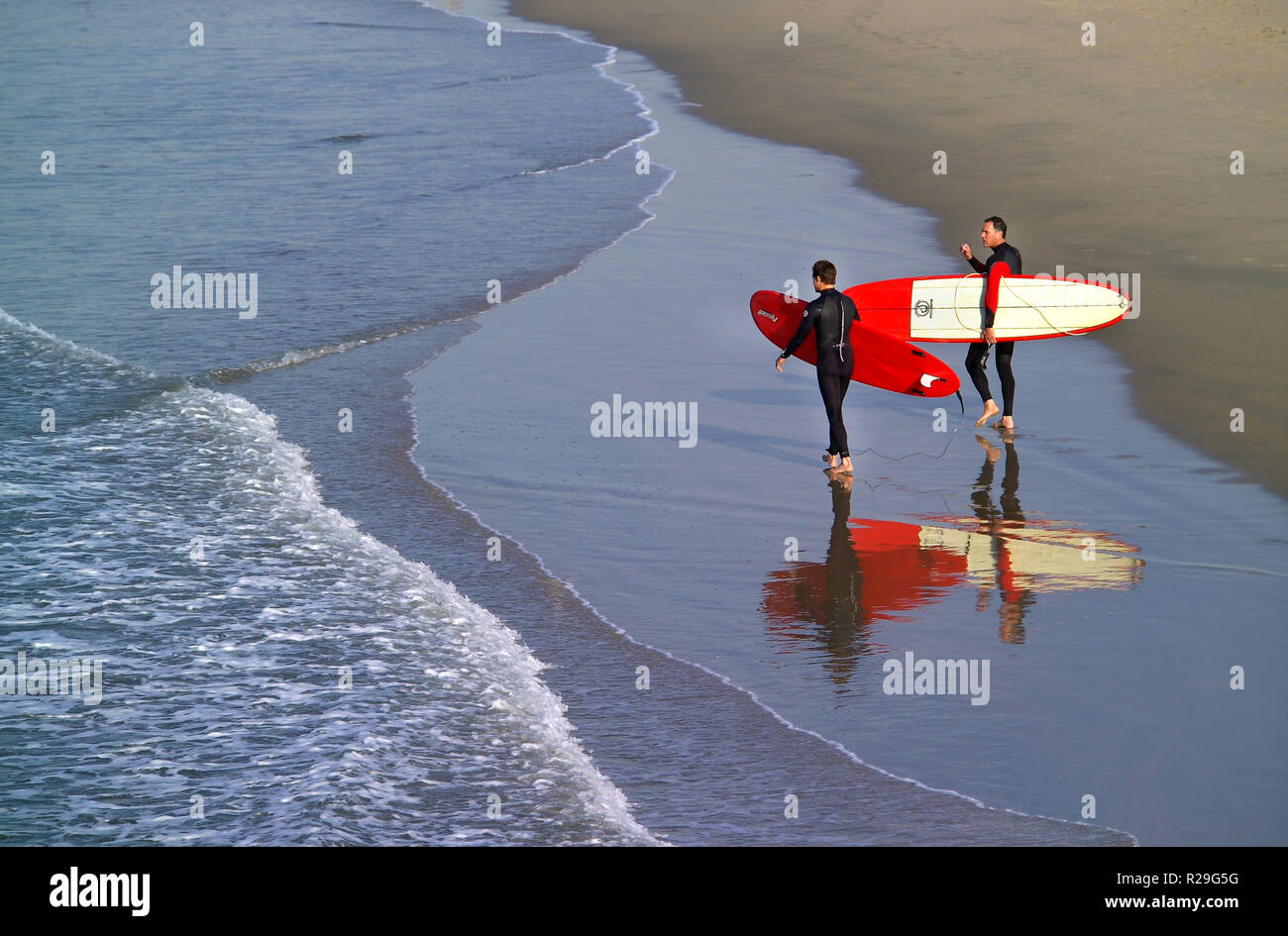 Two businessmen in wetsuits head from the beach at daybreak into the