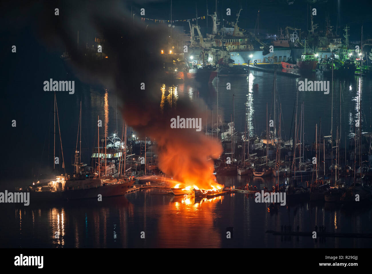 During the night, firefighters try to put out two luxury yachts that are catching fire at the marina berth Stock Photo