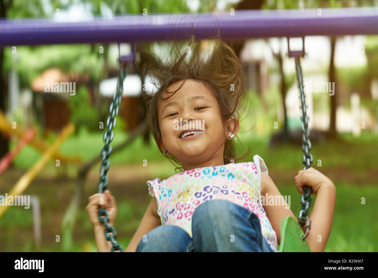 Asian girl swinging and smiling. Filipina kid Stock Photo