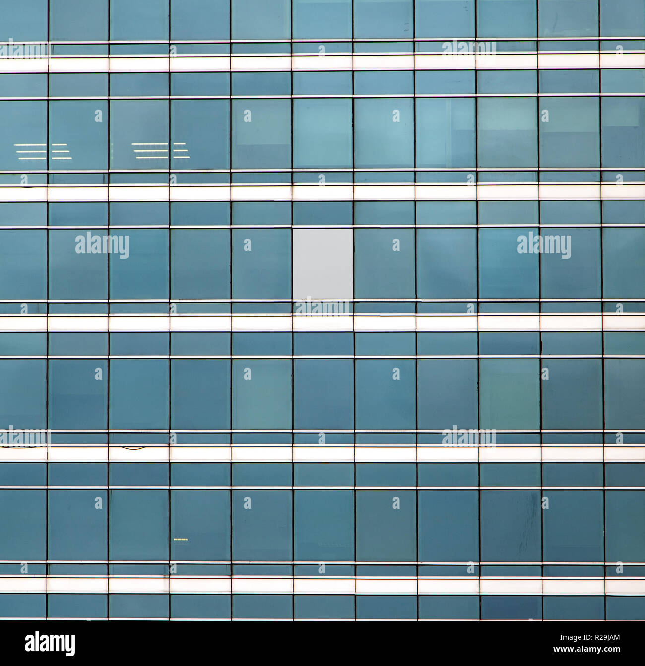 The glass facade of skyscraper with many identical windows and only one window is different. Same glasses structure of house wall with one exception - Stock Photo