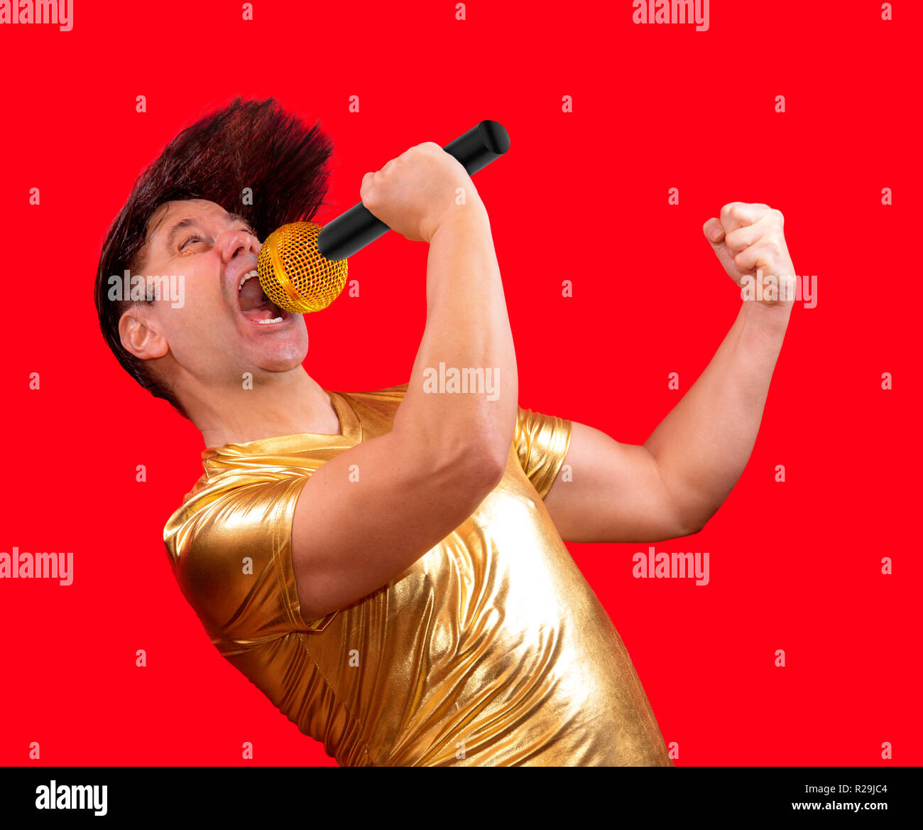 The excited singer with a microphone on red background. Crazy emotional man  in golden shirt sing to mic Stock Photo - Alamy