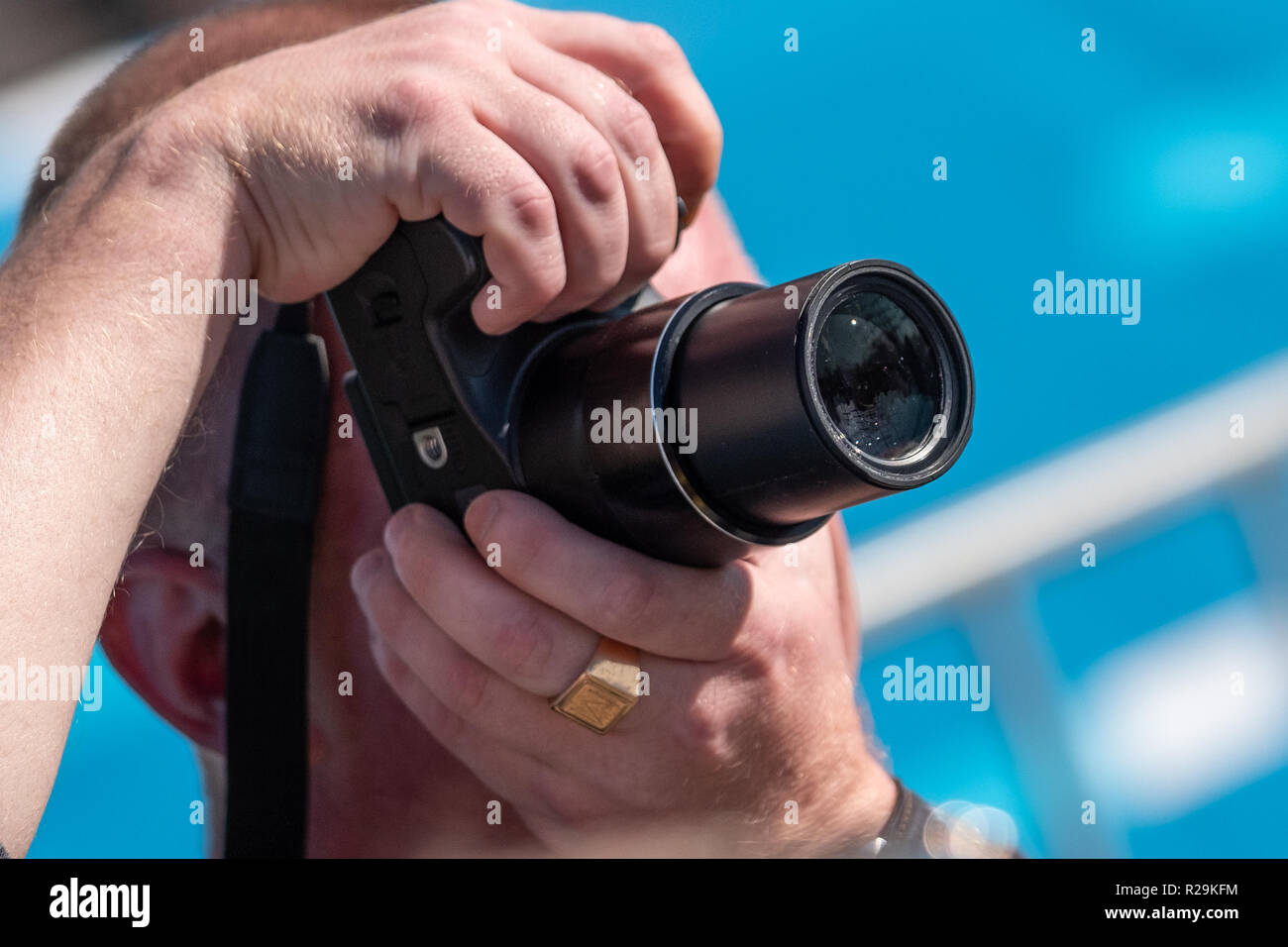 A man takes a picture with two hands holding a camera in front of his face. Stock Photo
