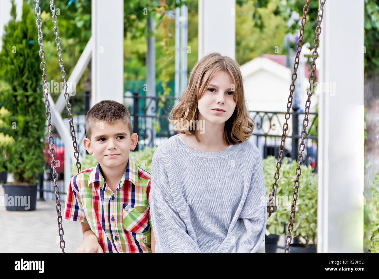 Cute brother and sister are riding on swing in summer Stock Photo - Alamy