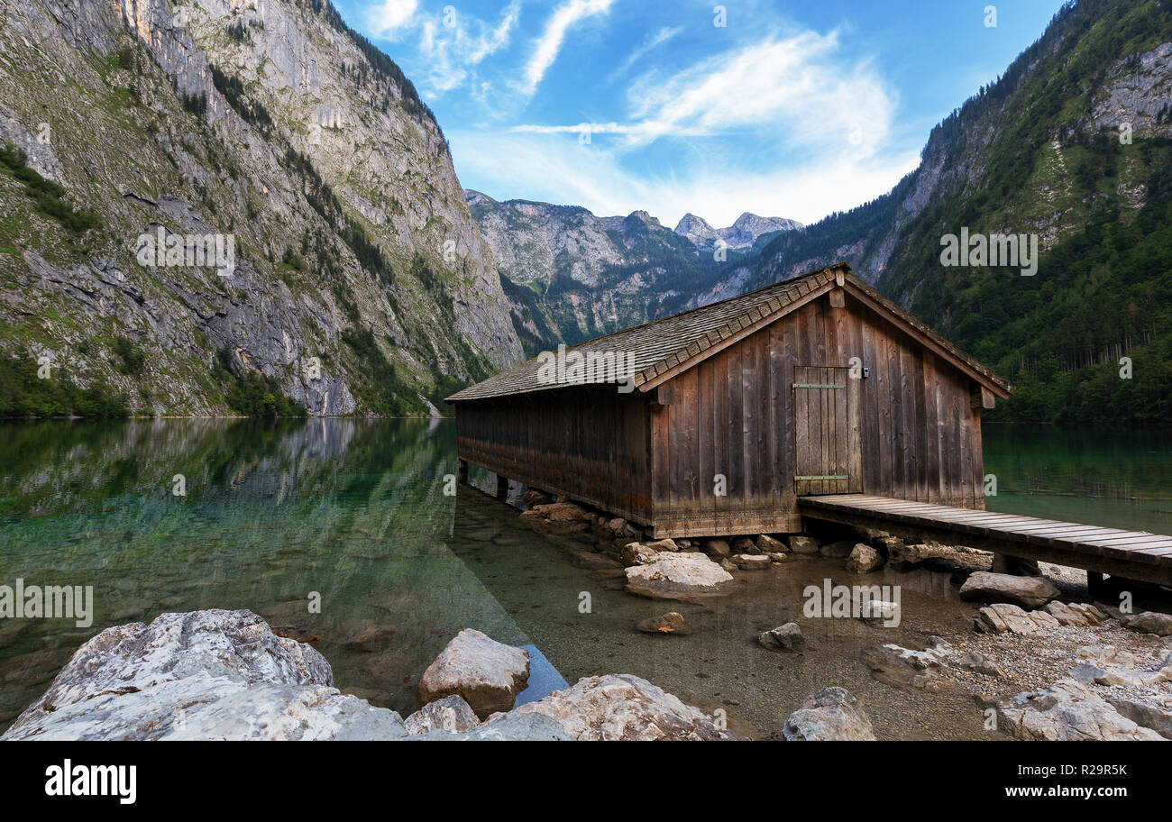 Panoramic view traditional old wooden boat house at scenic Lake Obersee on a beautiful day with foggy clouds in autumn, Bavaria, Germany Stock Photo