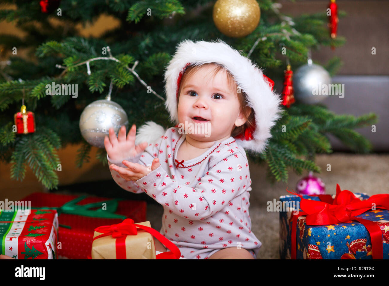 Funny baby girl in Santa hat in a holiday room Stock Photo