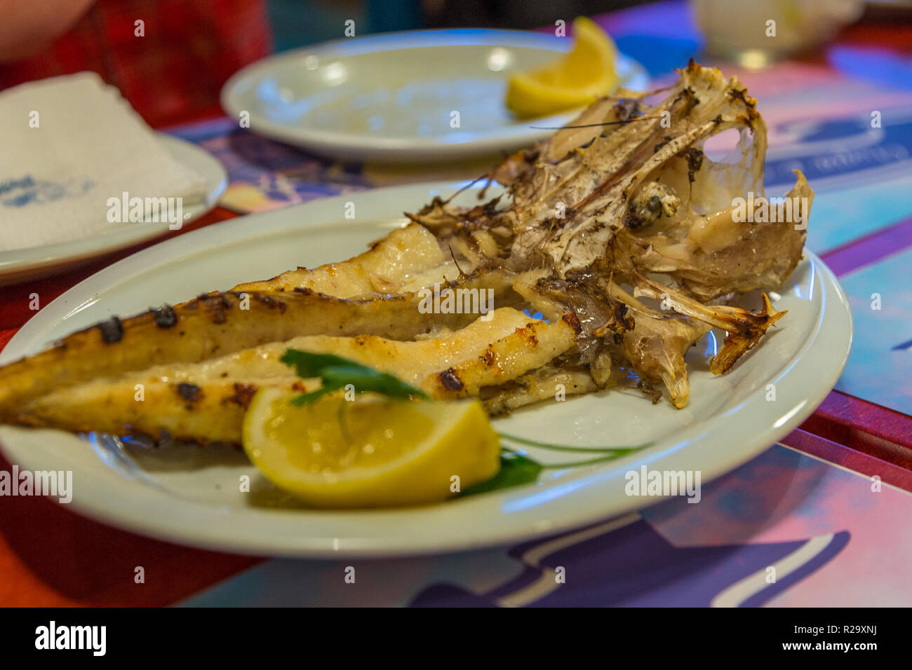 Grilled monkfish, sea fish, on a white plate with lemon. Restaurant in