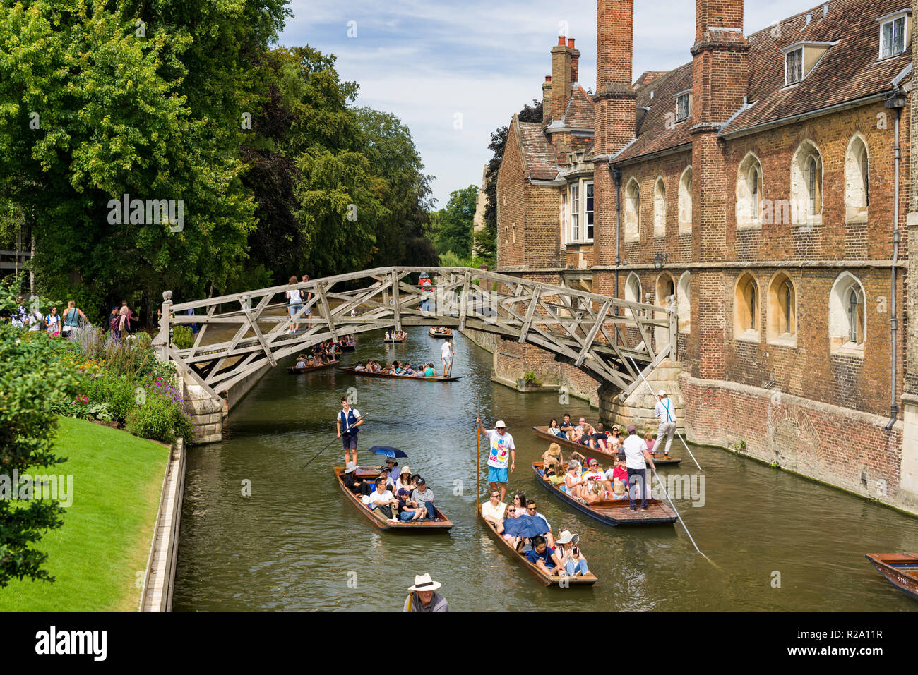 The famous and historic Mathematical wooden bridge with people walking on it as punt boats pass underneath on a sunny Summer day, Cambridge, UK Stock Photo