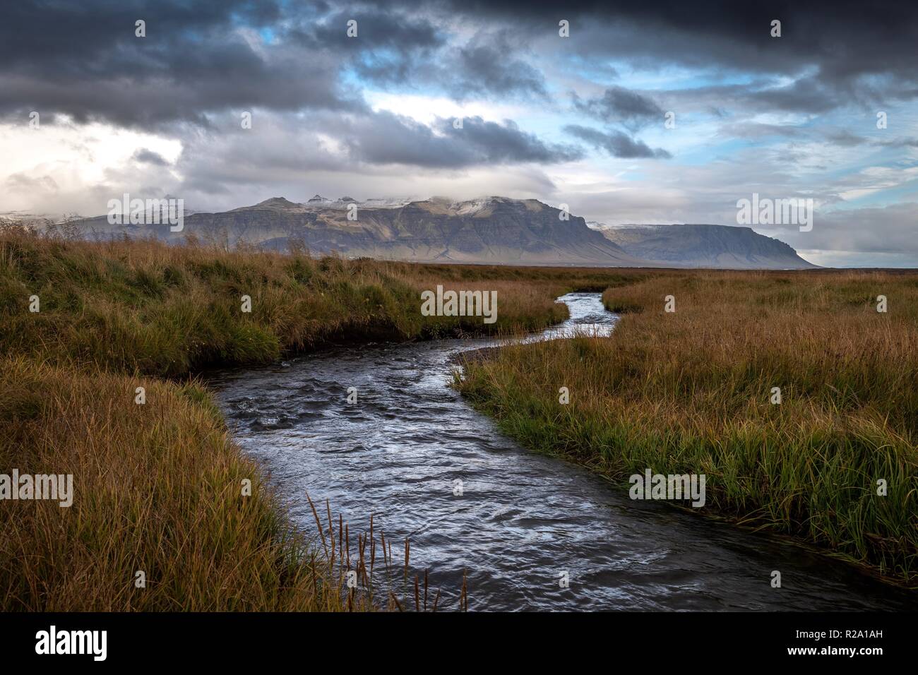 Stream in Iceland flows away from a distant mountain range. The stream can be used to represent strategic direction or vision for a business. Stock Photo
