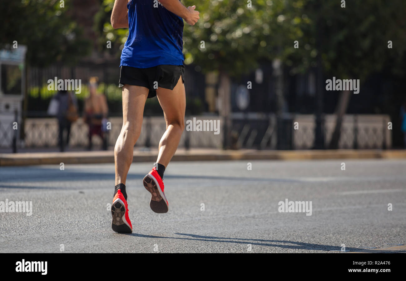 Running in the city roads. Young man runner, back view, blur background ...