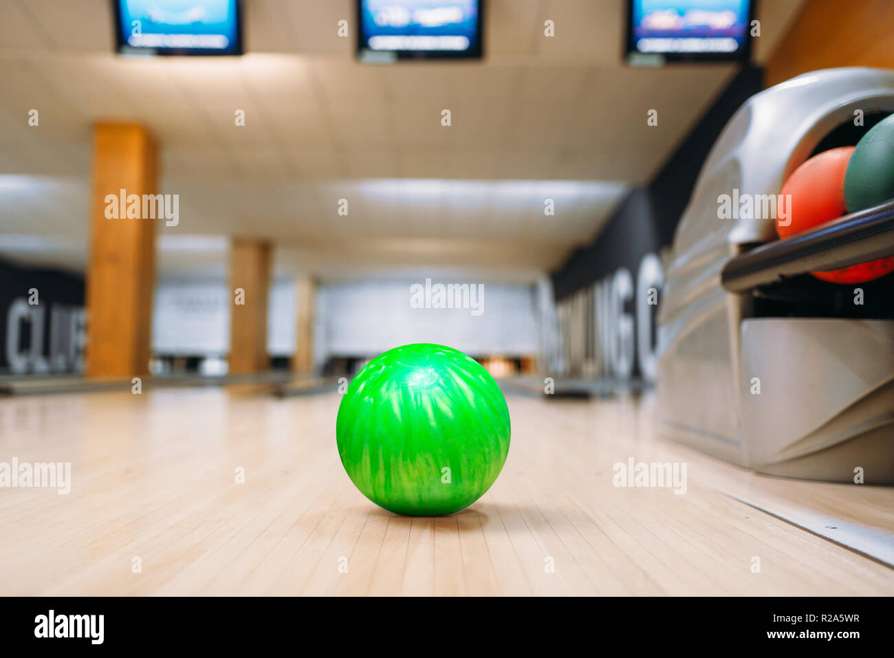 Green bowling ball on wooden floor in club, closeup view, nobody. Bowl game concept Stock Photo