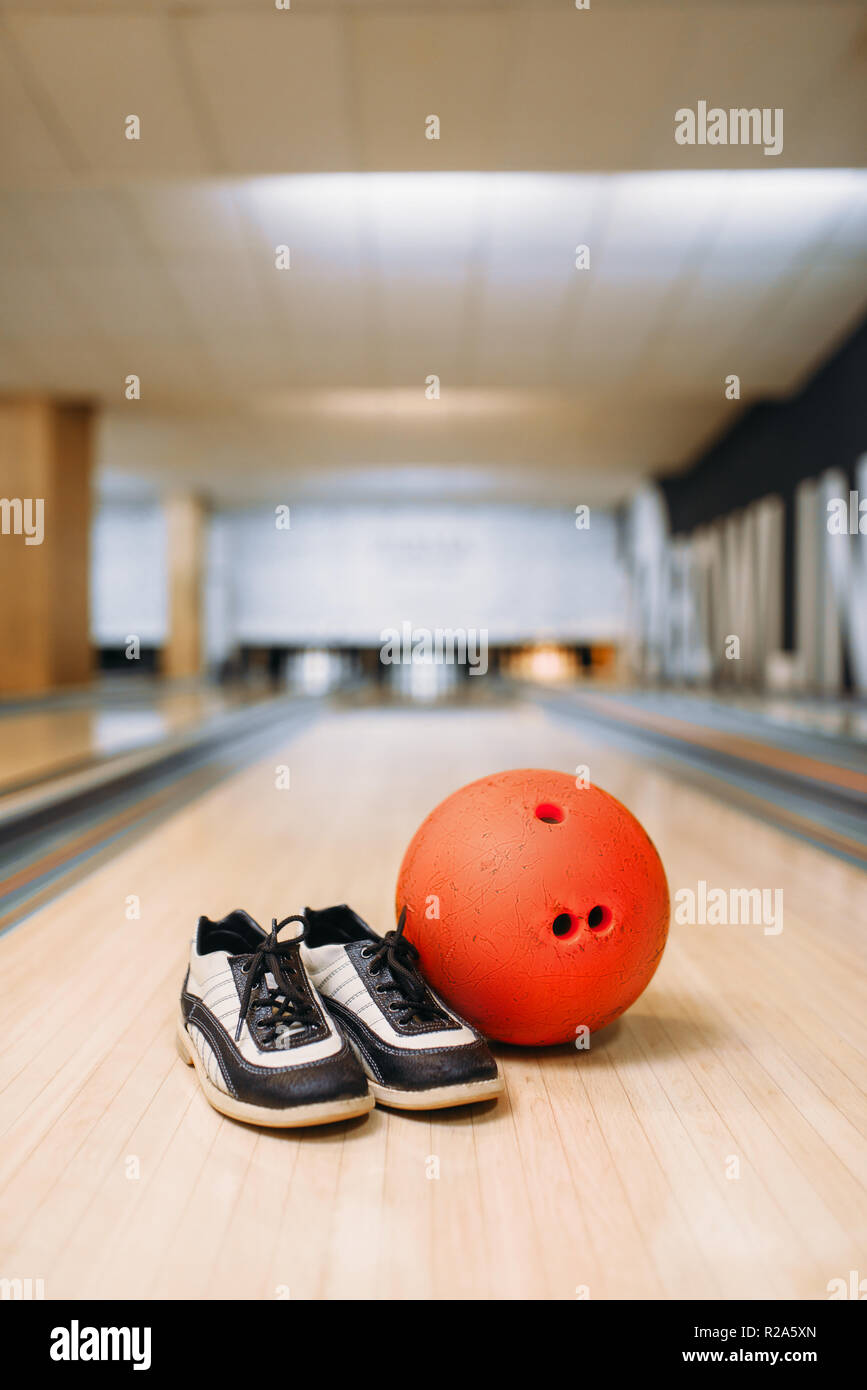 Bowling ball and house shoes on lane in club, pins on background, nobody. Bowl game concept, tenpin Stock Photo