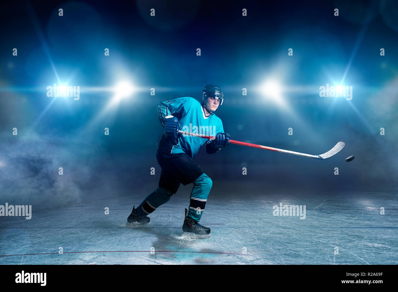 Hockey player with stick and puck makes a throw, ice arena, spotlights