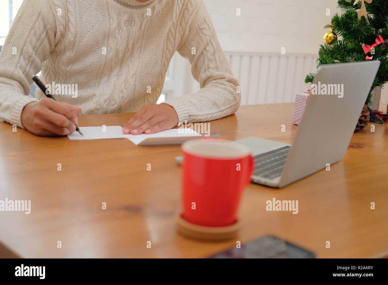 man wearing cream sweater writing christmas letter greeting card ...
