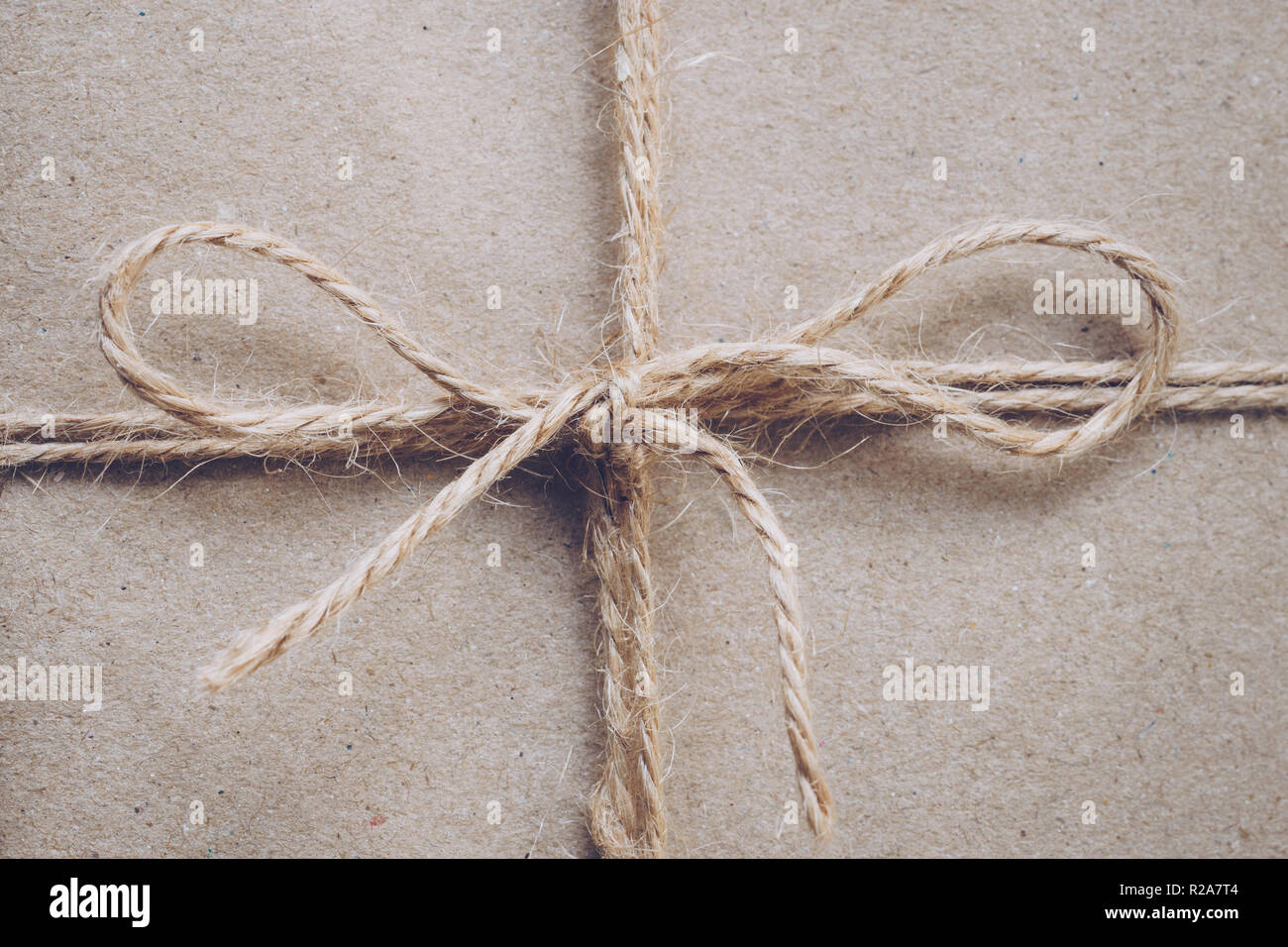 String or twine tied in a bow on kraft paper texture Stock Photo