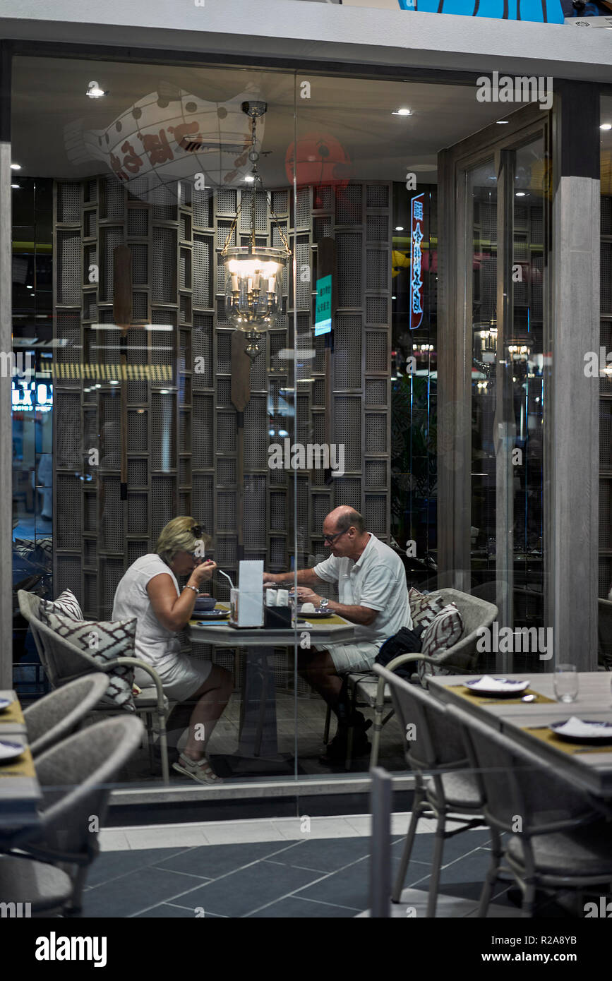 Couple dining. Mature couple eating out at a restaurant and seen through the encased interior window Stock Photo