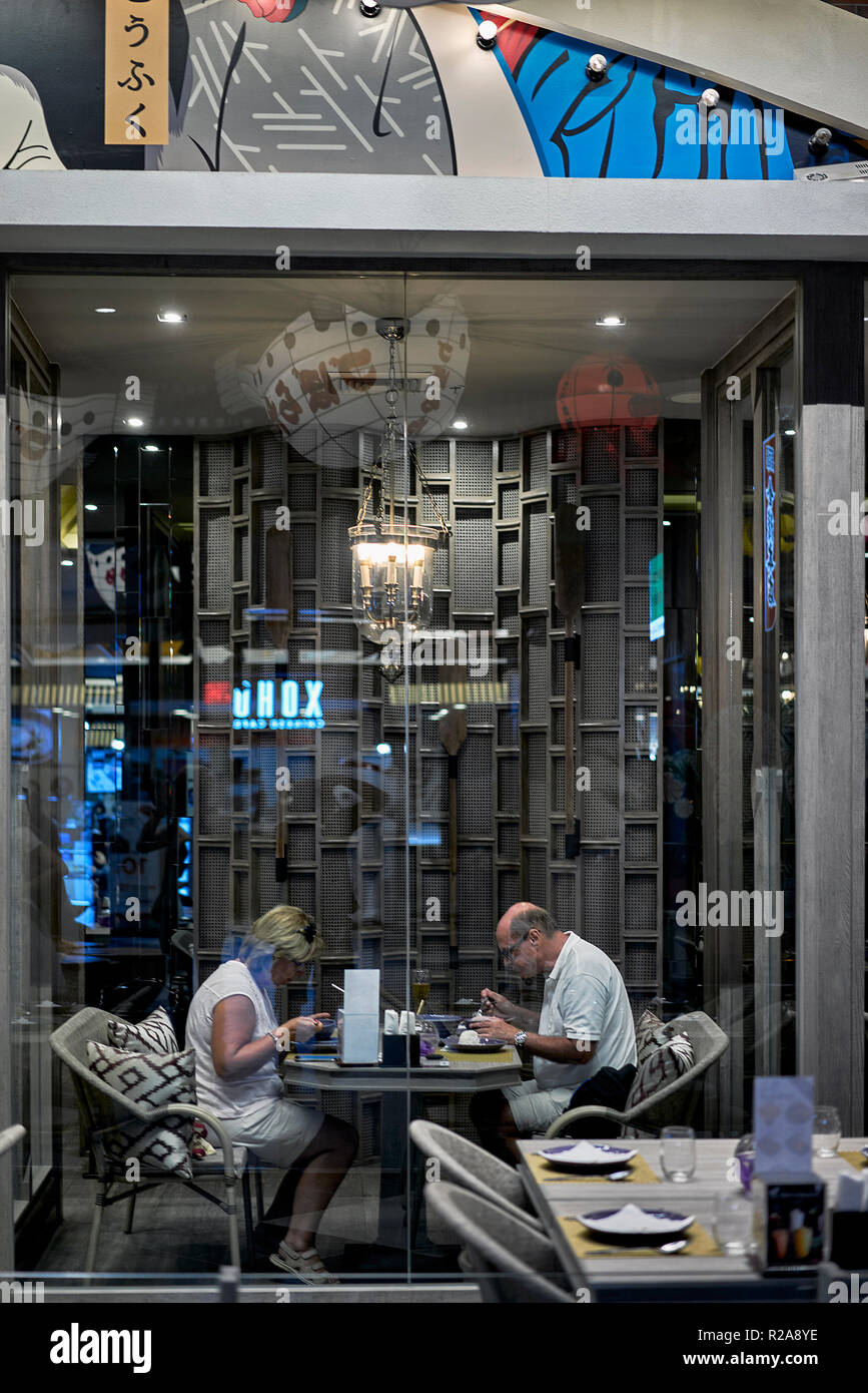 Couple dining. Mature couple eating out at a restaurant and seen through the encased interior window Stock Photo