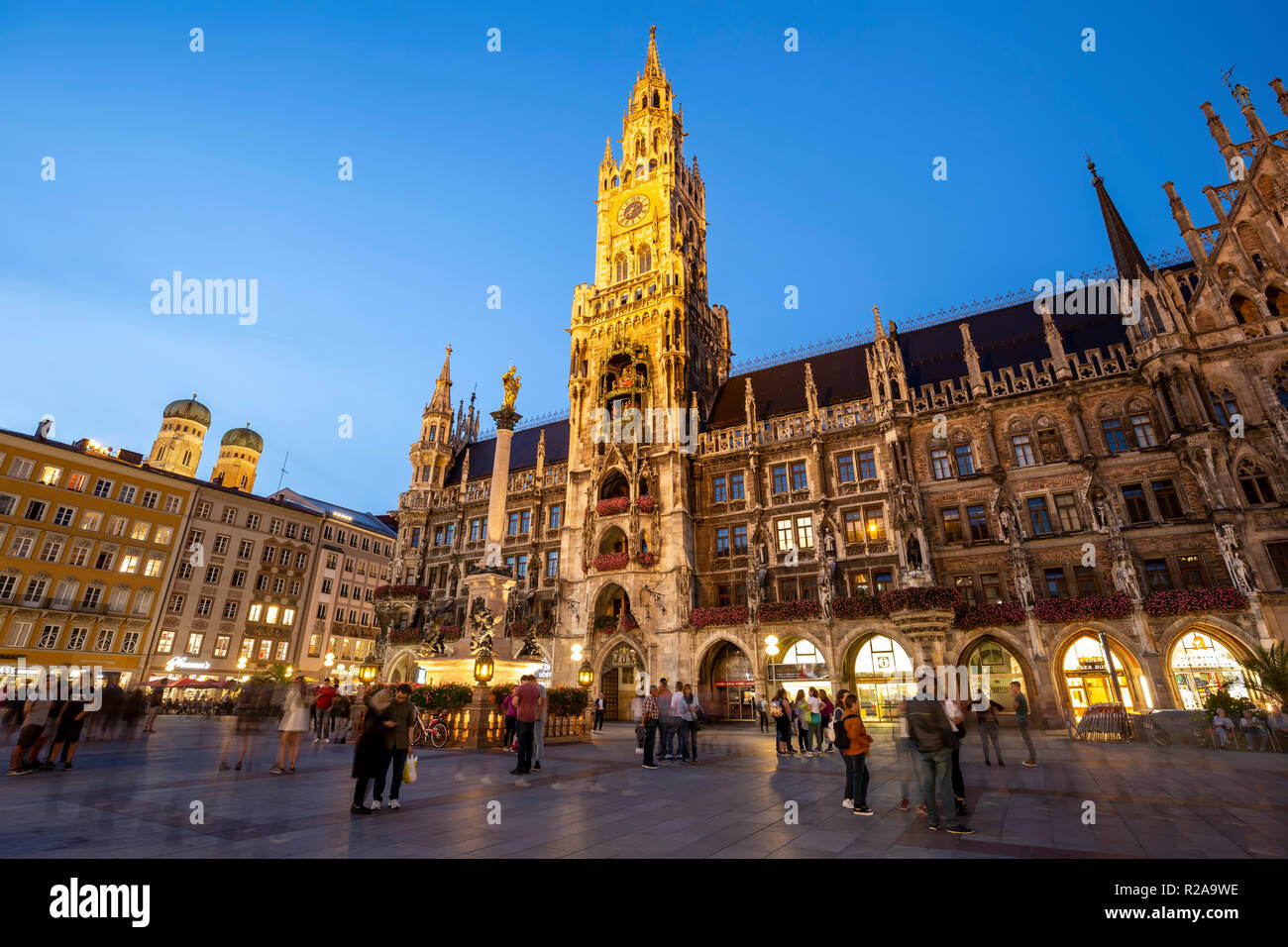New Town Hall (featuring clock tower and Glockenspiel) and crowd (domed towers of Frauenkirche at left), Marienplatz, Munich, Germany Stock Photo