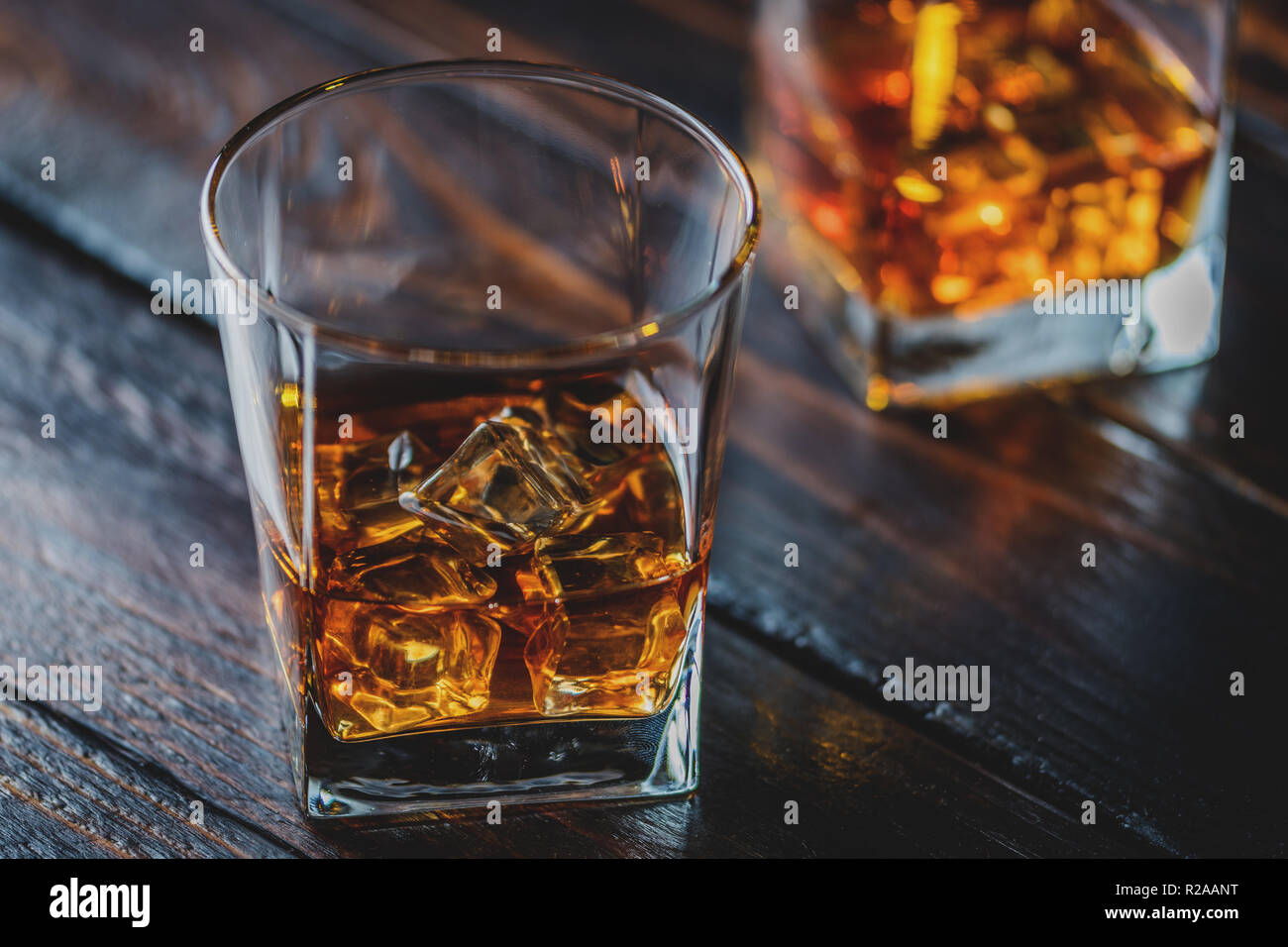 Alcohol drink whisky, whiskey or bourbon with ice cubes on dark wood