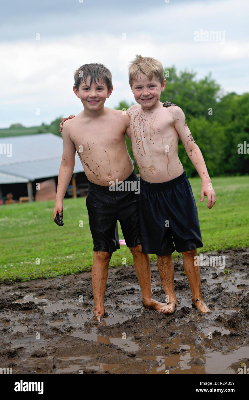 brothers with arms around each other before mud fight Stock Photo