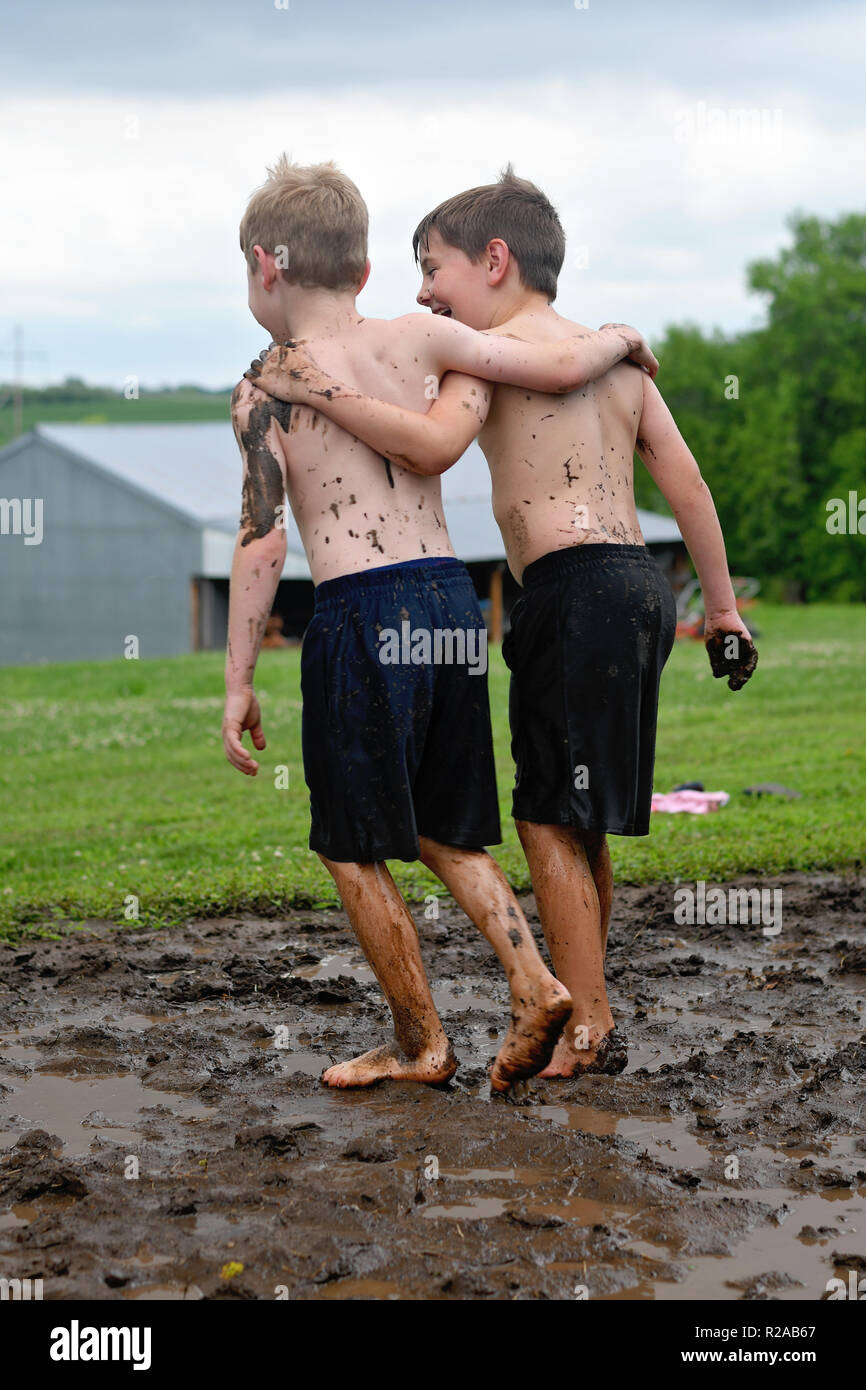 brothers with arms around each other before mud fight Stock Photo Alamy