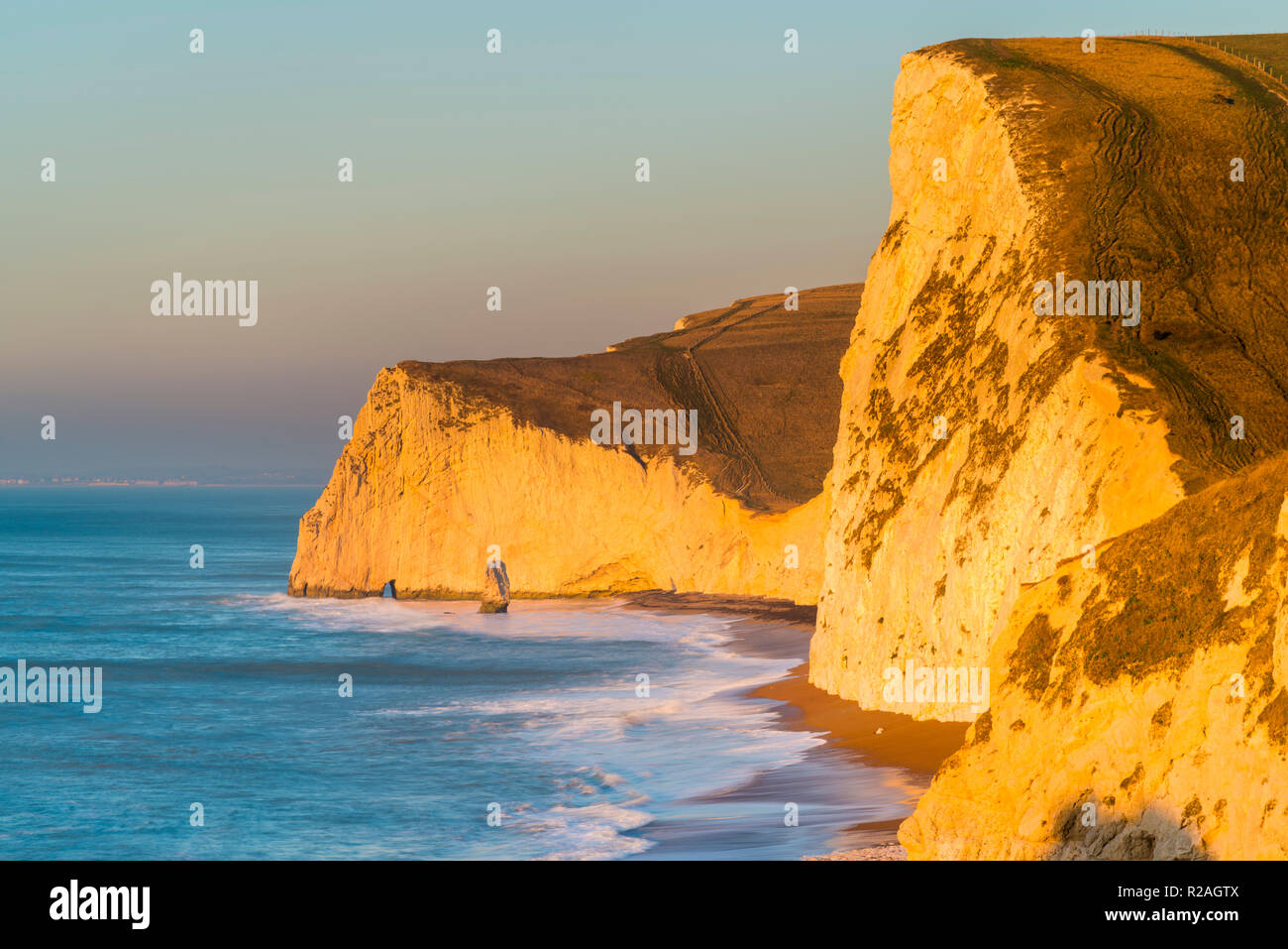 Lulworth, Dorset, UK.  18th November 2018.  The chalk cliffs of Swyre Head and Bats Head on the Jurassic Coast of Dorset near Lulworth glow in the early morning golden sunlight shortly after sunrise on a cold clear day.  Picture Credit: Graham Hunt/Alamy Live News. Stock Photo