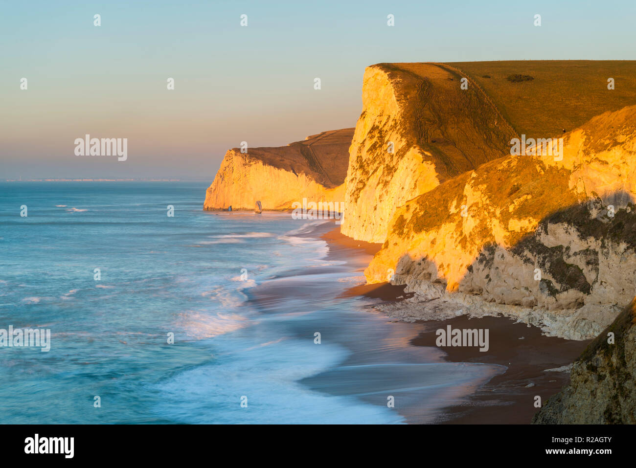 Lulworth, Dorset, UK.  18th November 2018.  The chalk cliffs of Swyre Head and Bats Head on the Jurassic Coast of Dorset near Lulworth glow in the early morning golden sunlight shortly after sunrise on a cold clear day.  Picture Credit: Graham Hunt/Alamy Live News. Stock Photo