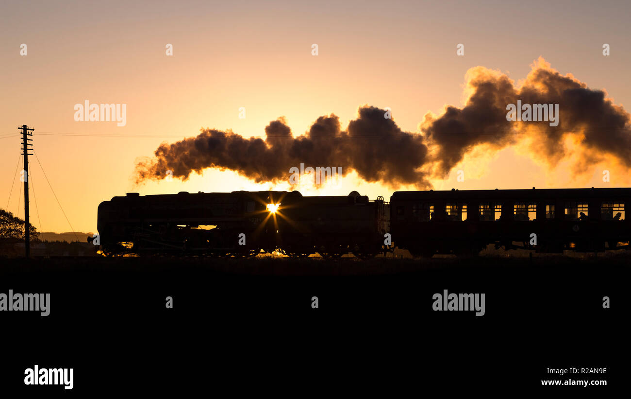 Leicestershire, UK. 18th November 2018. British Railways Standard Class 9F 2-10-0 'Leicester City' hauls a passenger train during sunset on the Great Central Railway, Quorn & Woodhouse, Loughborough, Leicestershire, UK. 18th November 2018. Photograph by Richard Holmes. Credit: Richard Holmes/Alamy Live News Stock Photo