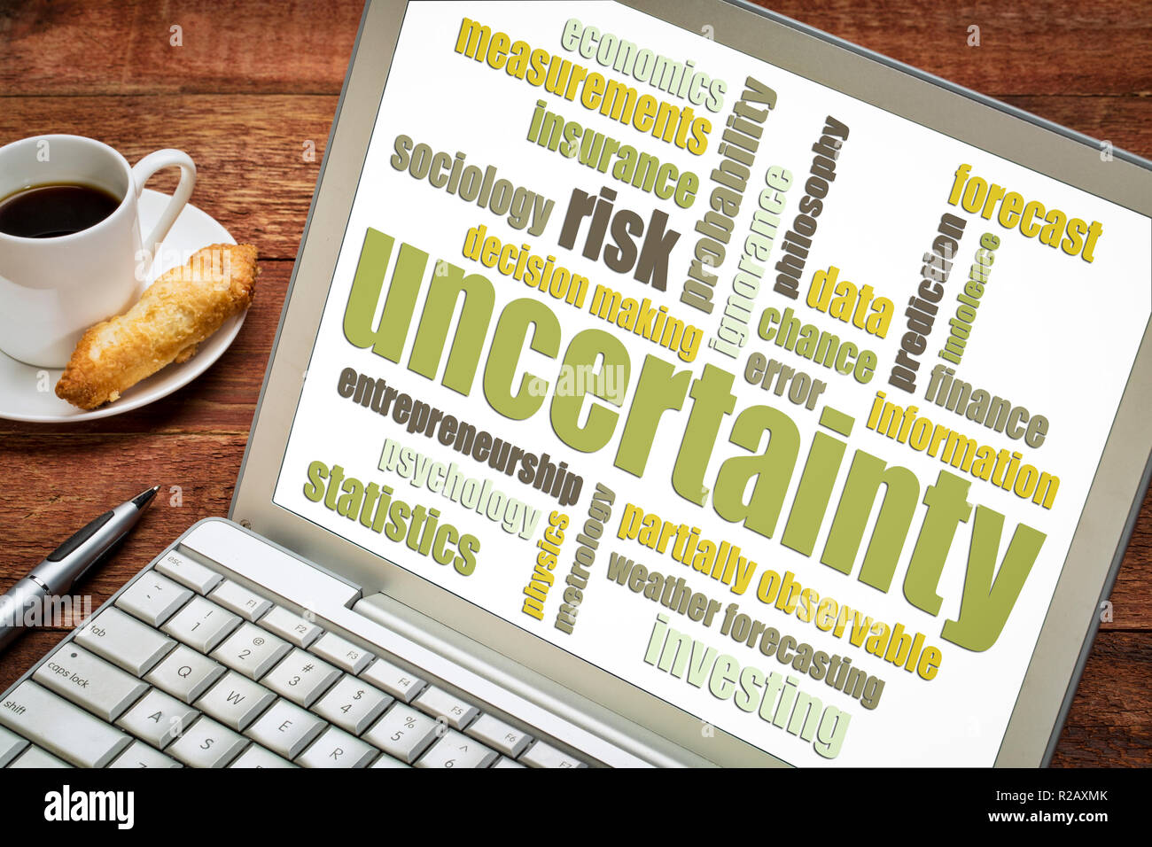 uncertainty and risk word cloud on a laptop with a cup of coffee Stock Photo
