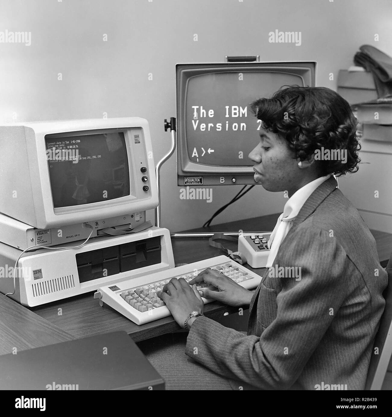 An African American woman works on an early IBM computer, ca. 1982. Stock Photo