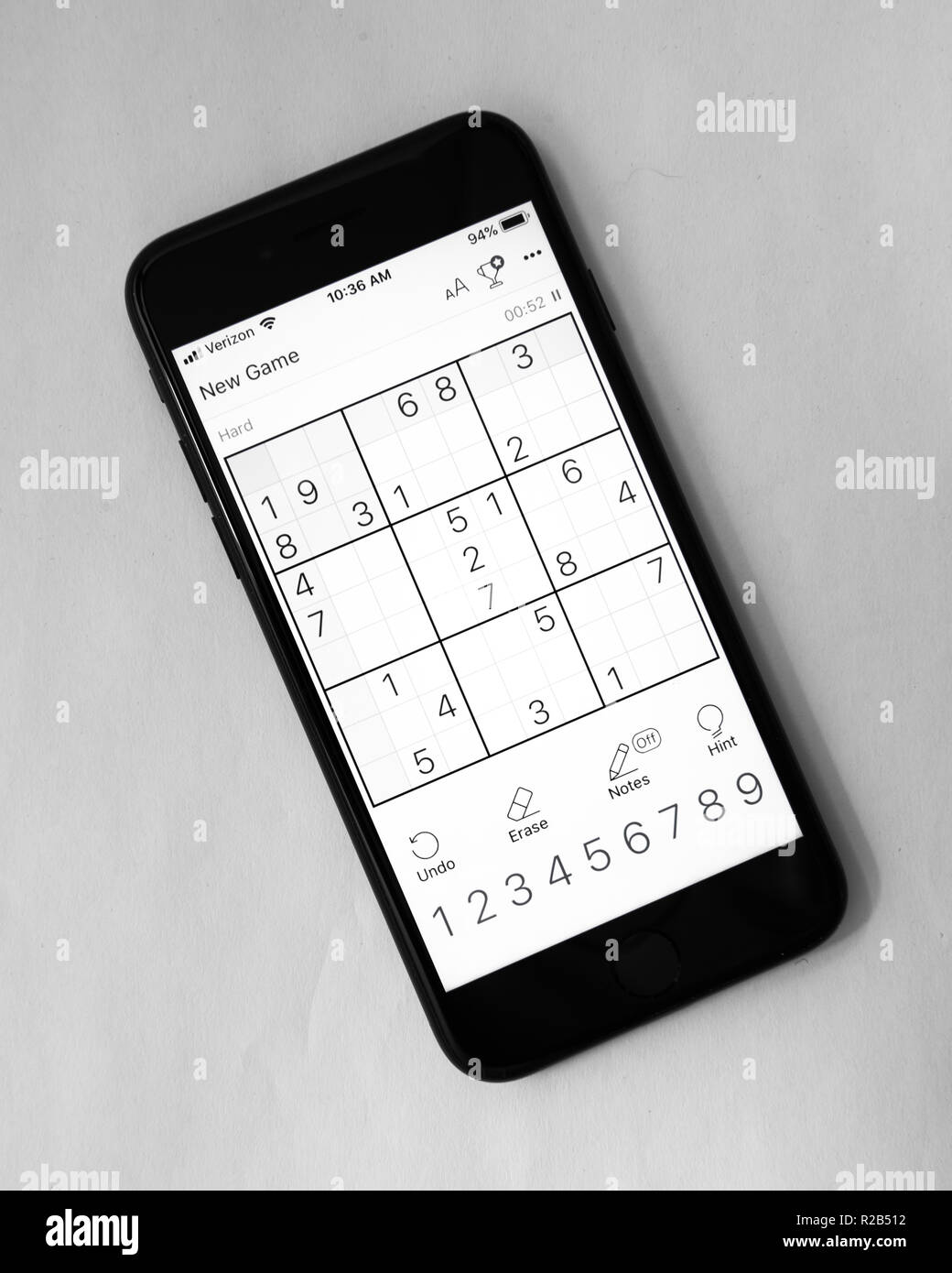 A black iPhone 7 with the screen showing a hard level Sudoku game. Stock Photo