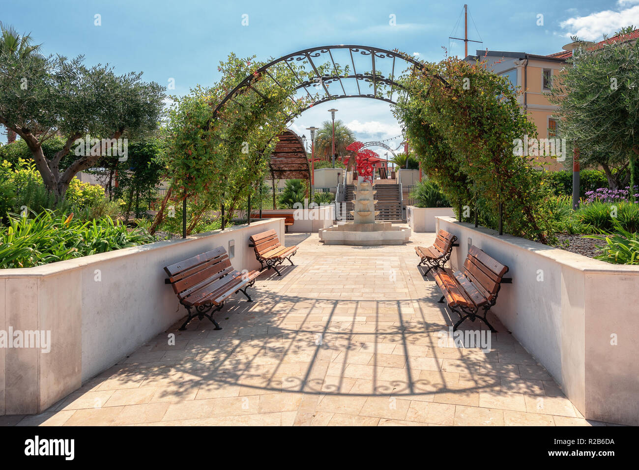 Saint-Jean-Cap-Ferrat, France, September 4, 2018:  Impression of the city garden with fountain decorated with a red piece of modern art of the village Stock Photo