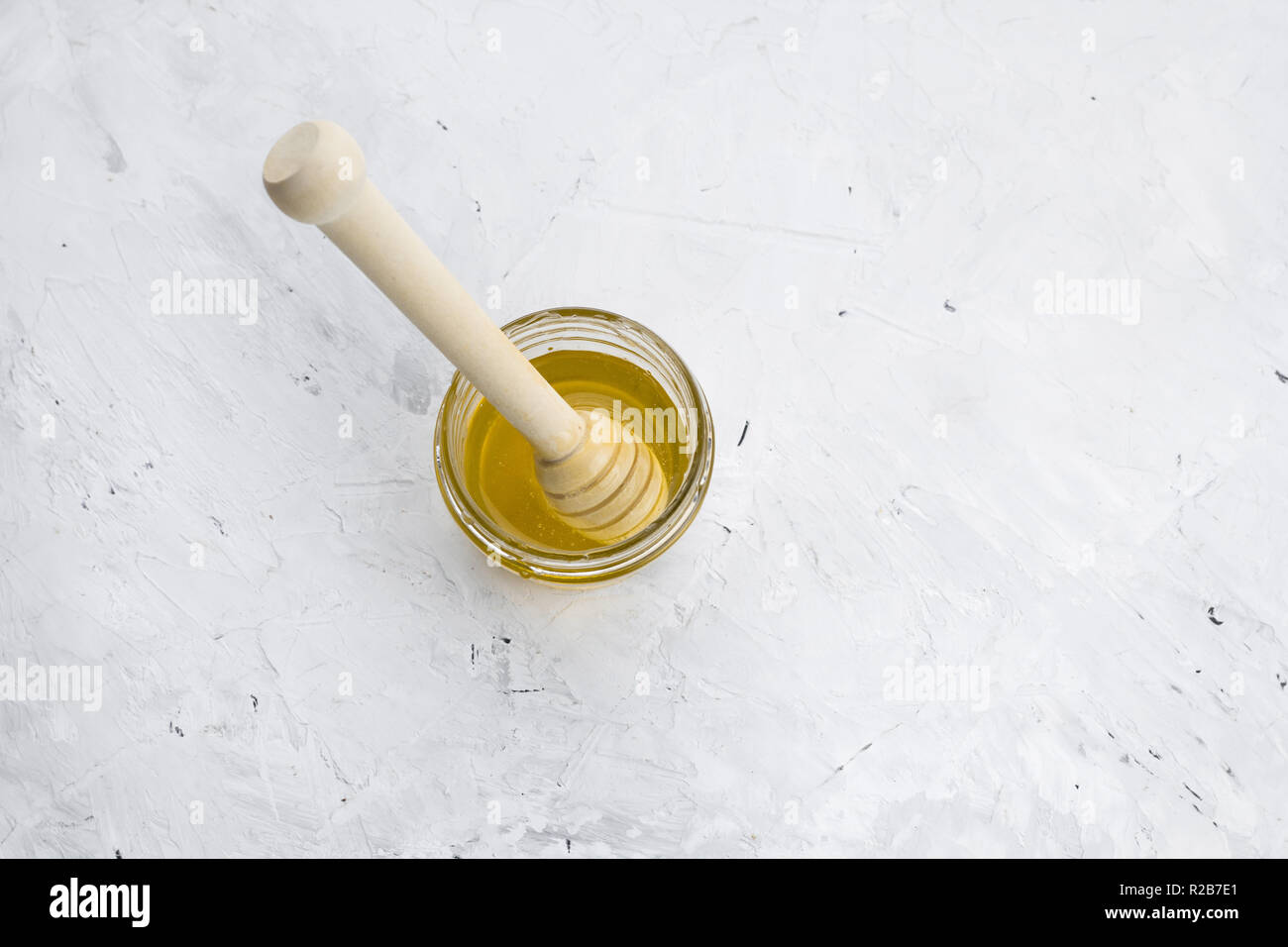 top view honey jar with wooden spoon  on a white concrete shabby  background Stock Photo