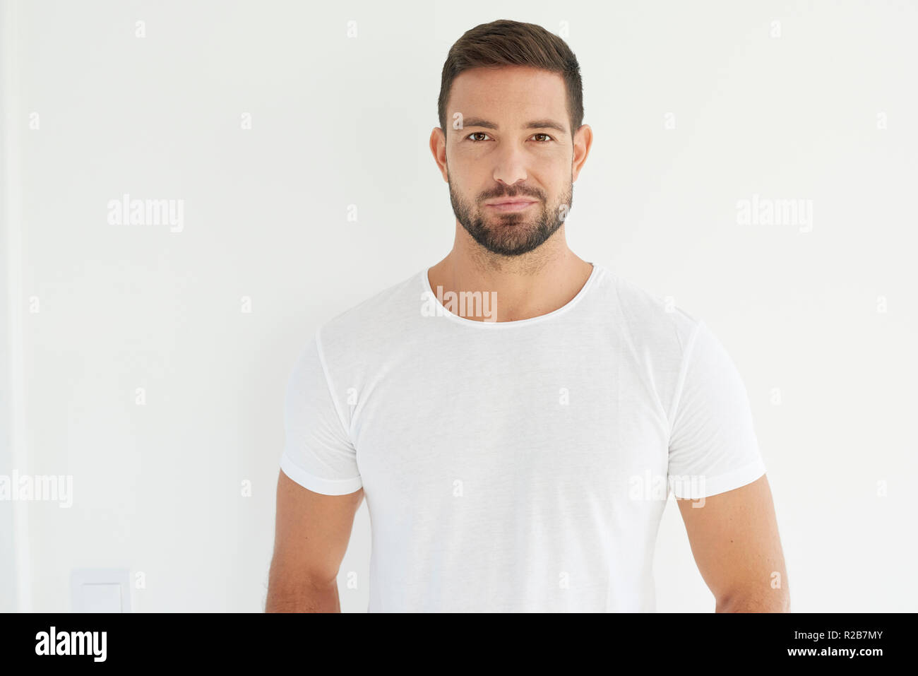 Studio portrait of handsome young man wearing white t shirt while ...