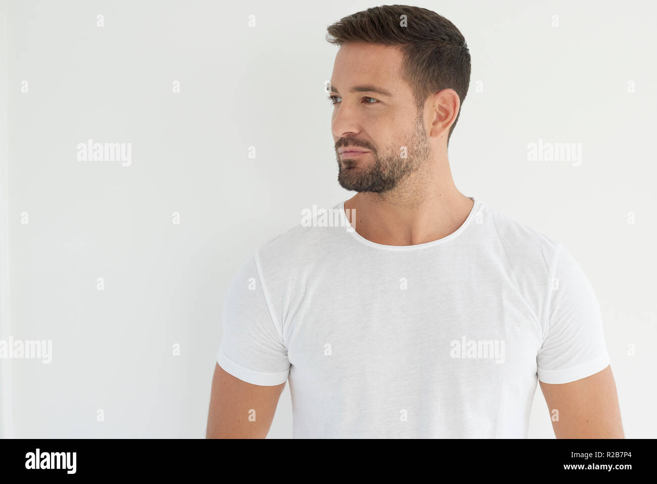 Studio portrait of handsome young man wearing white t shirt and looking ...