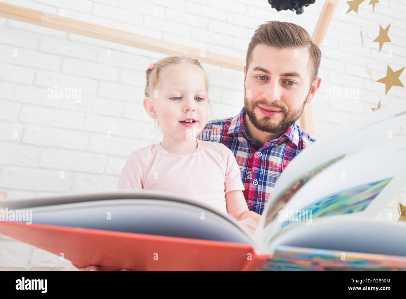 Dad and daughter sit together and read a book. Stock Photo