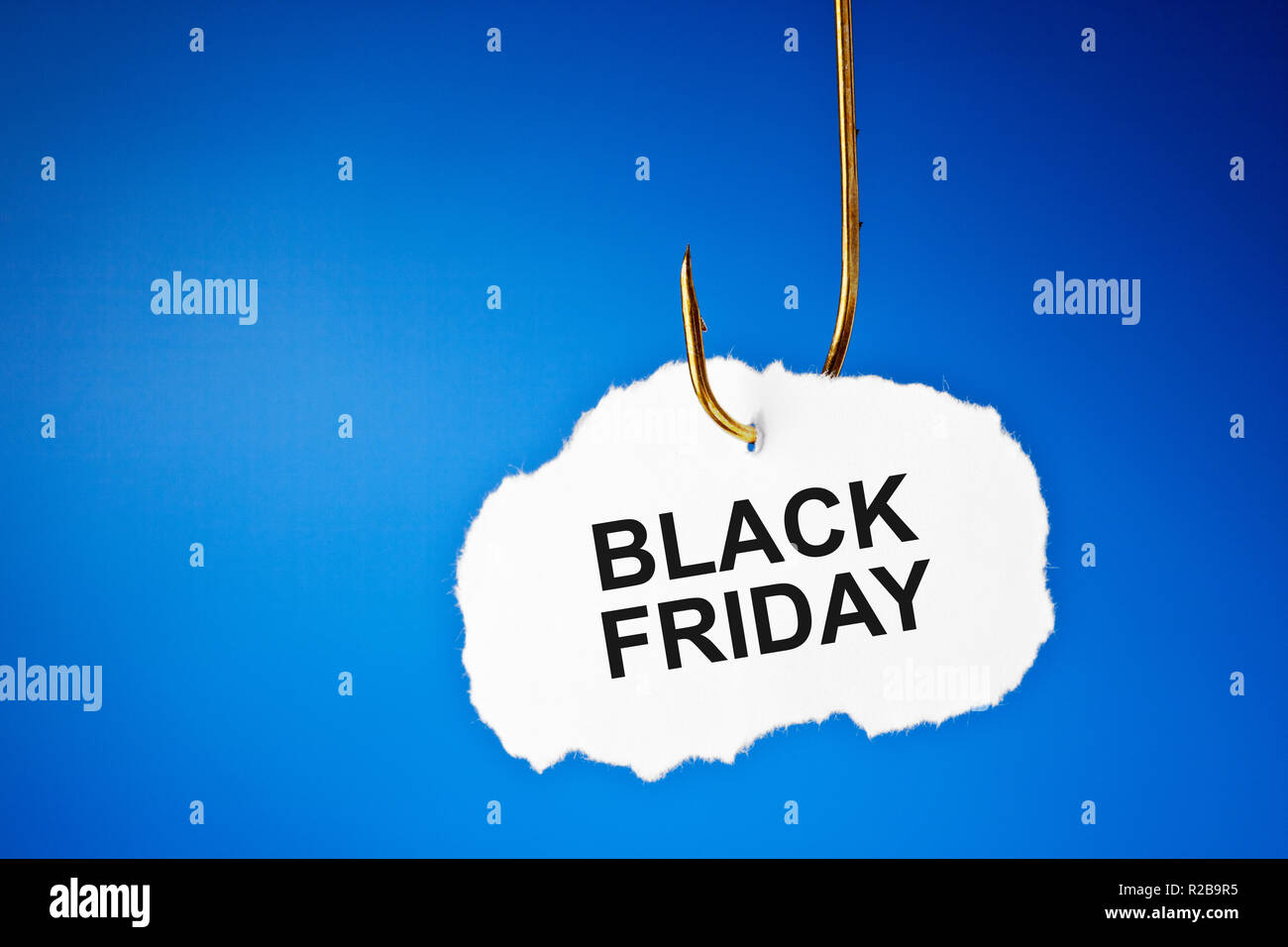 Text Black Friday hanging on a fishing hook over blue background. Beware of the Black Friday sale trap concept. Stock Photo