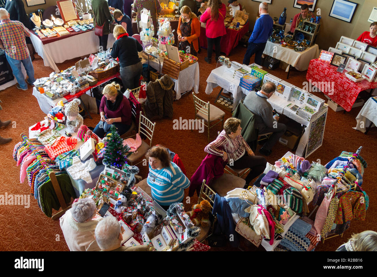shoppers browsing for gifts and stall holders at an indoor craft market Stock Photo