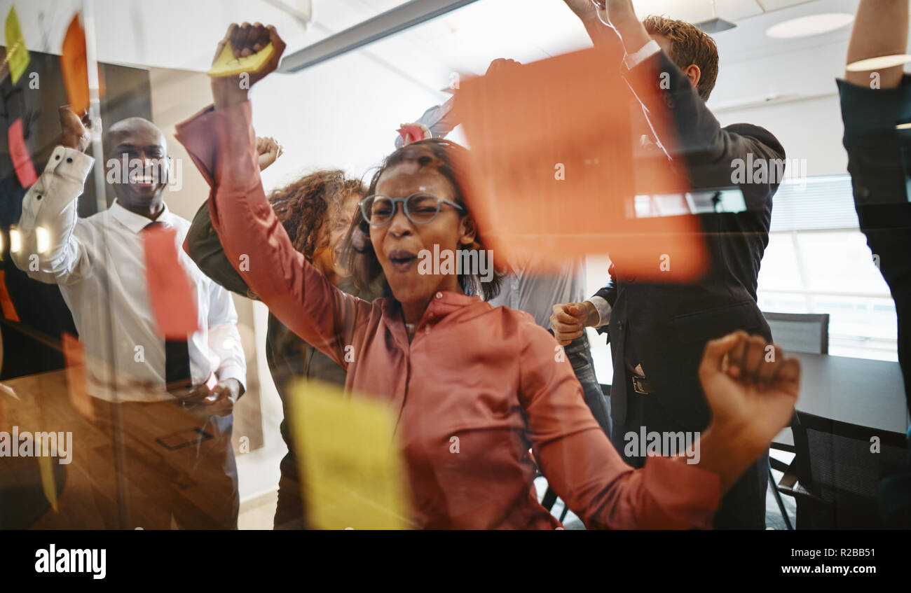 Diverse group of ecstatic businesspeople cheering together over a ...