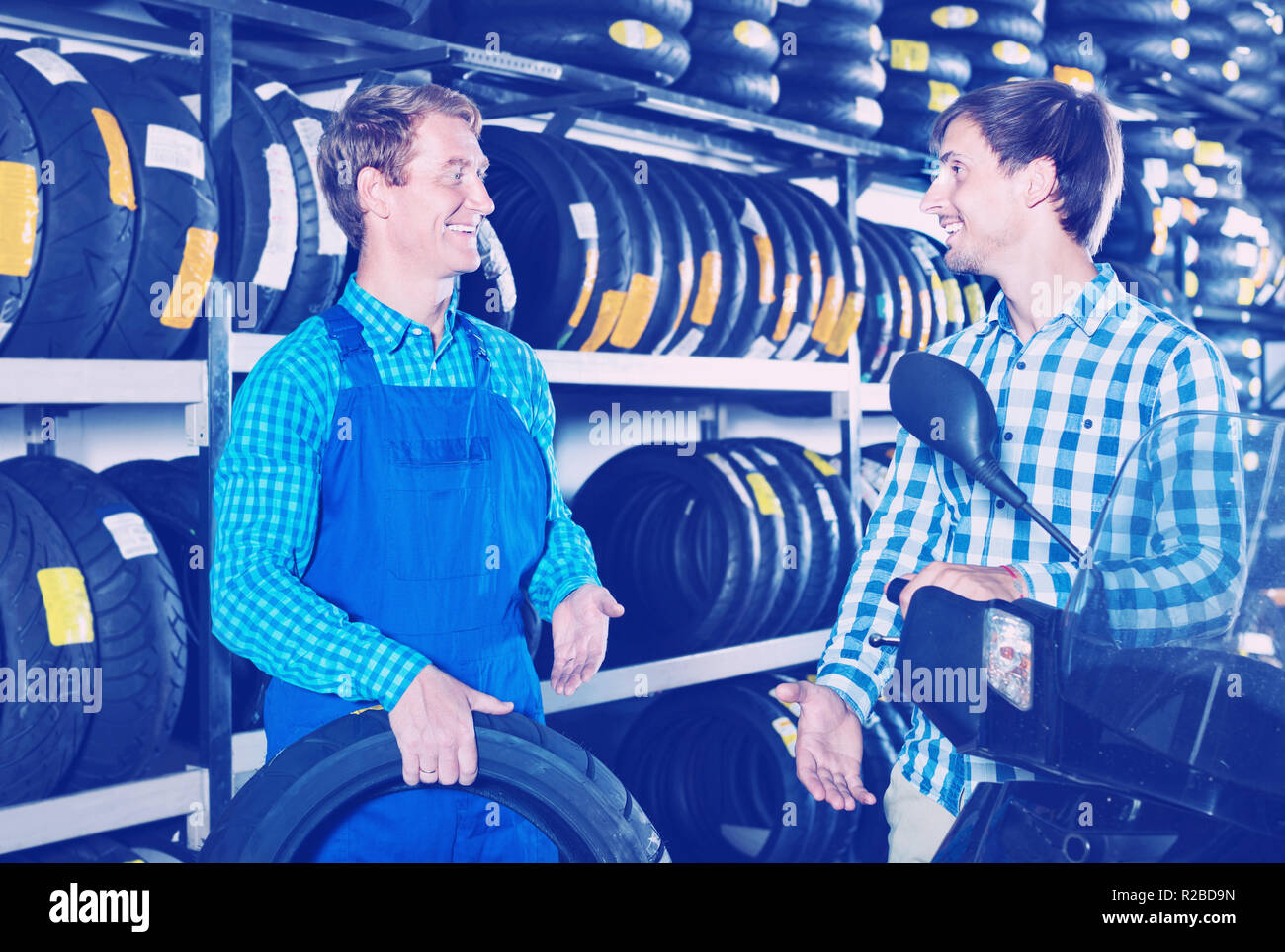Portrait of diligent mechanic and smiling friendly customer chatting