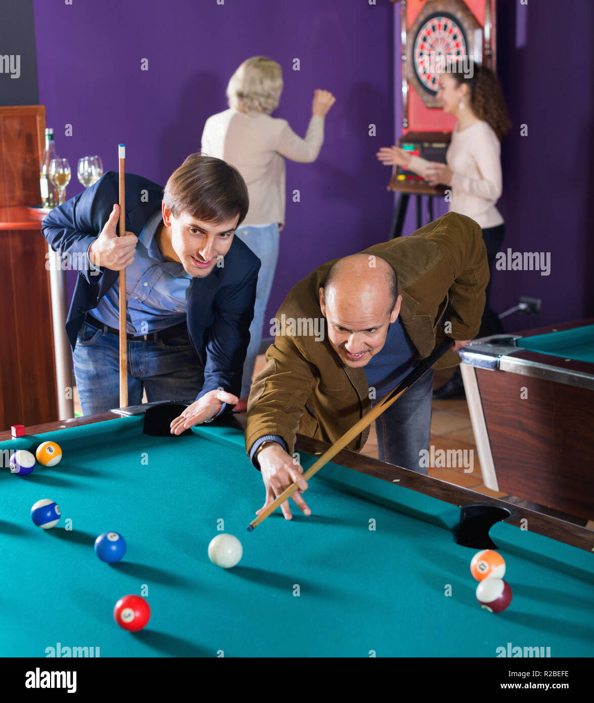 Relaxed happy positive people playing billiard and darts as hanging out